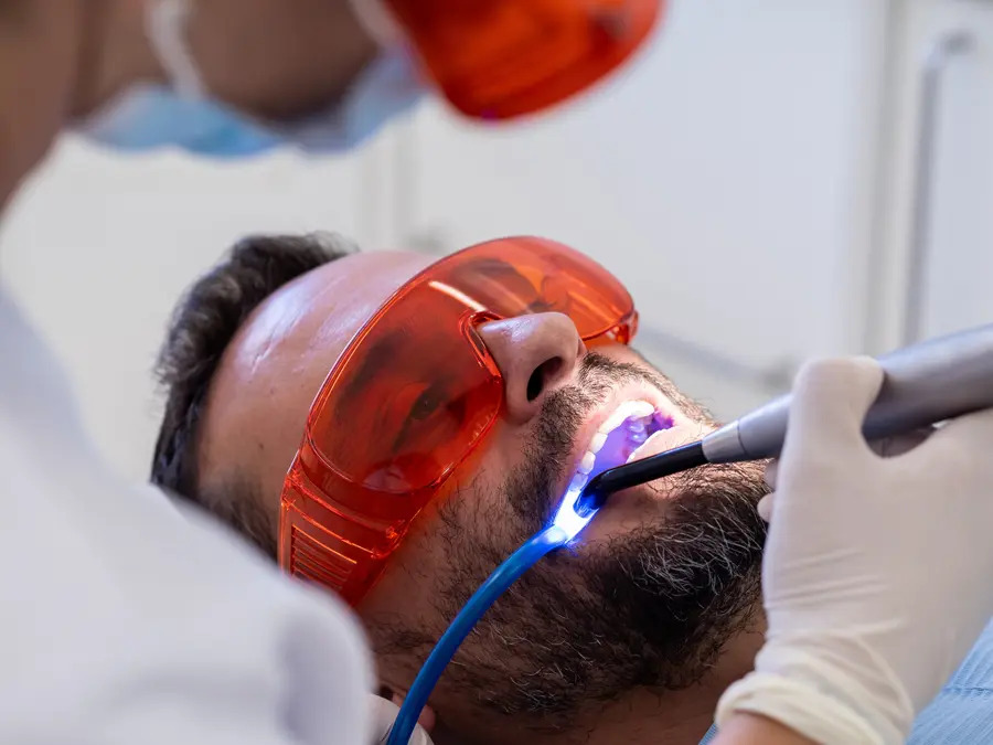 A dentist performing a professional teeth-whitening procedure, showcasing the range of dental services available. From preventive care to cosmetic enhancements, this image highlights the expertise and advanced technology that ensure patients receive comprehensive, high-quality dental treatments.