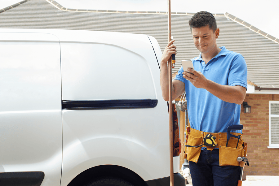 A professional plumber in a tool belt stands beside a service van, checking his phone with a satisfied expression. The image conveys clear pricing and easy booking, highlighting how modern plumbing services offer transparent quotes and seamless appointment scheduling for customer convenience.