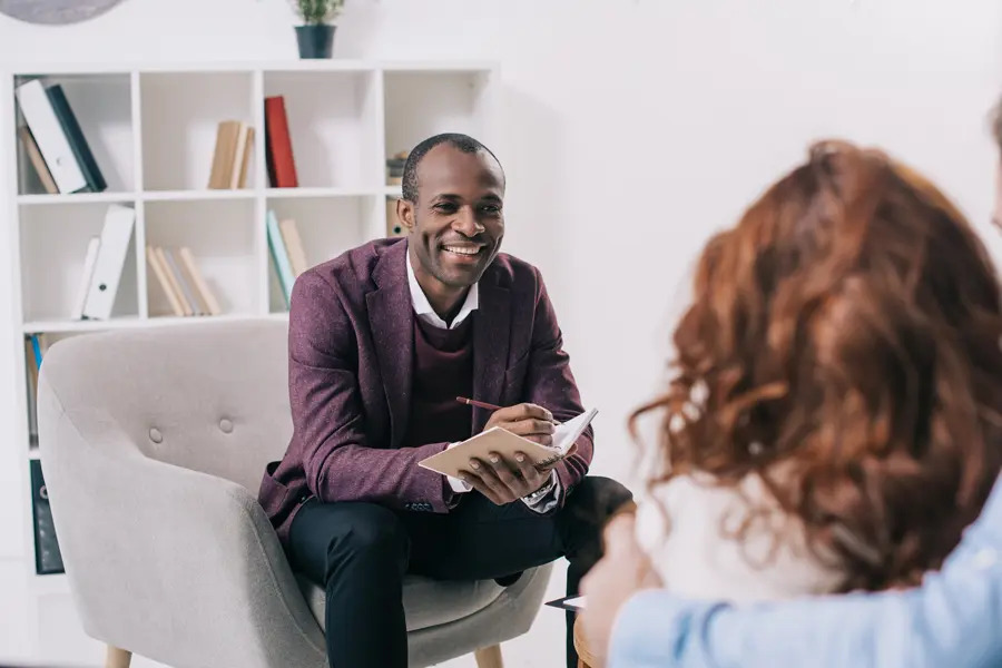 A skilled therapist listening attentively to clients in a comfortable setting, offering guidance with a warm smile. Their expertise and knowledge shine through as they create a safe, supportive space, helping individuals navigate their challenges and work towards emotional well-being and growth.
