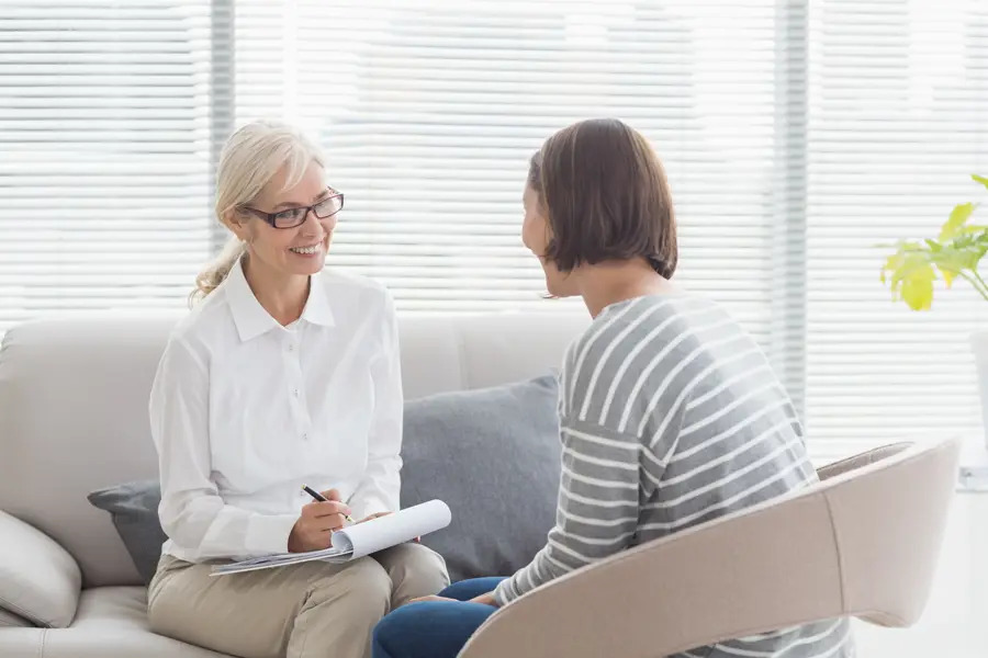 A warm and welcoming therapist engaging with a client in a comfortable setting, providing a listening ear and compassionate care. The positive, supportive environment reflects the strong reputation and trusted testimonials, helping clients feel heard and supported on their journey toward healing.